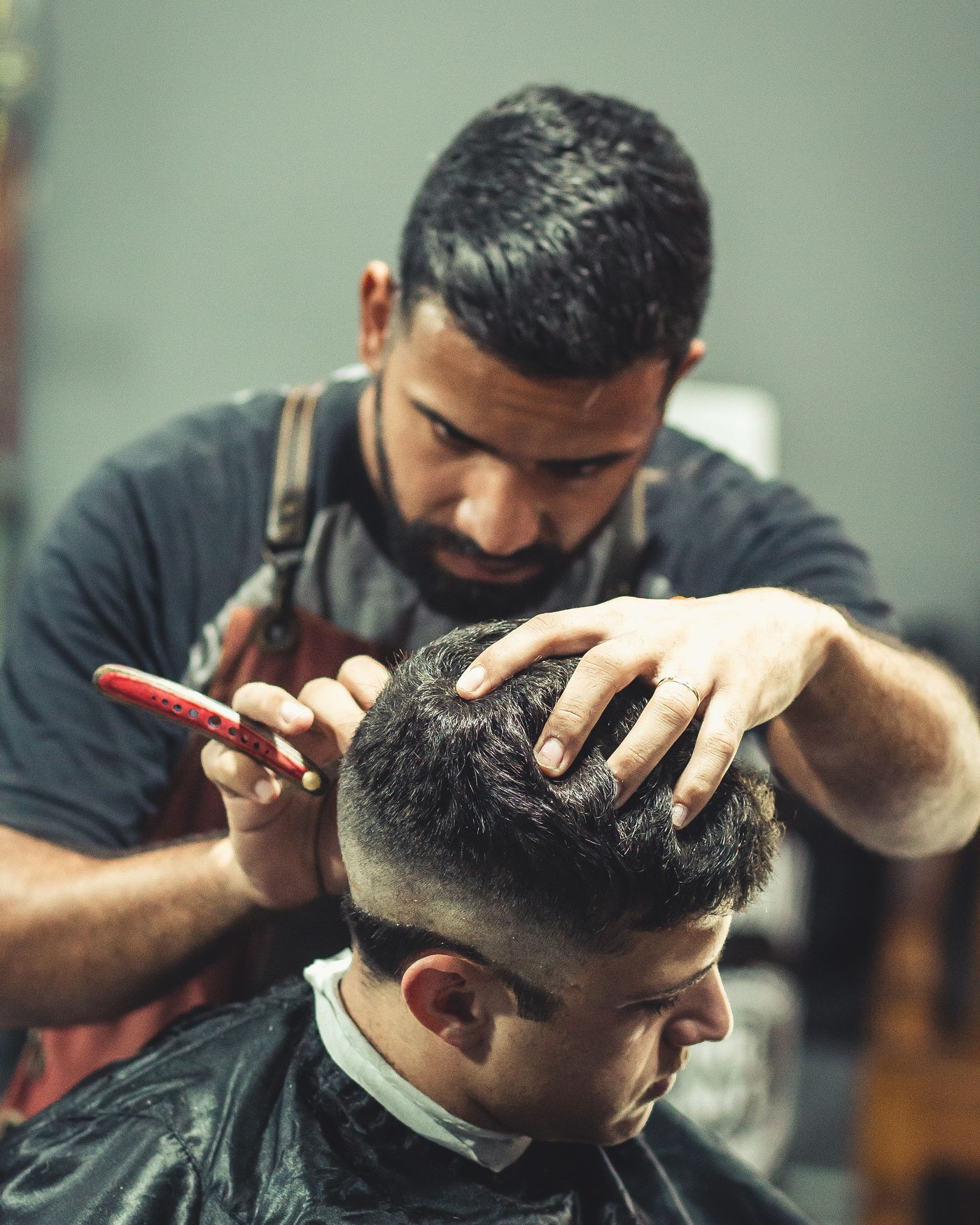 A barber working on a client's hairline